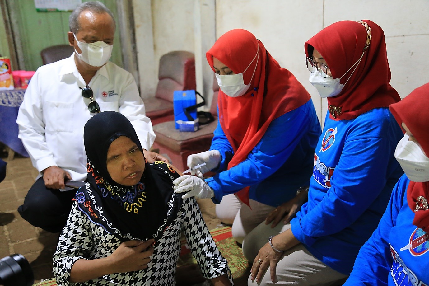 Health workers and the Head of the Tayu 2 Health Center, Imbang Tri Hanekowati, administer COVID-19 vaccination to Suyati at her home in Kedungbang Village, Central Java (photo by: AIHSP Documentation Team).